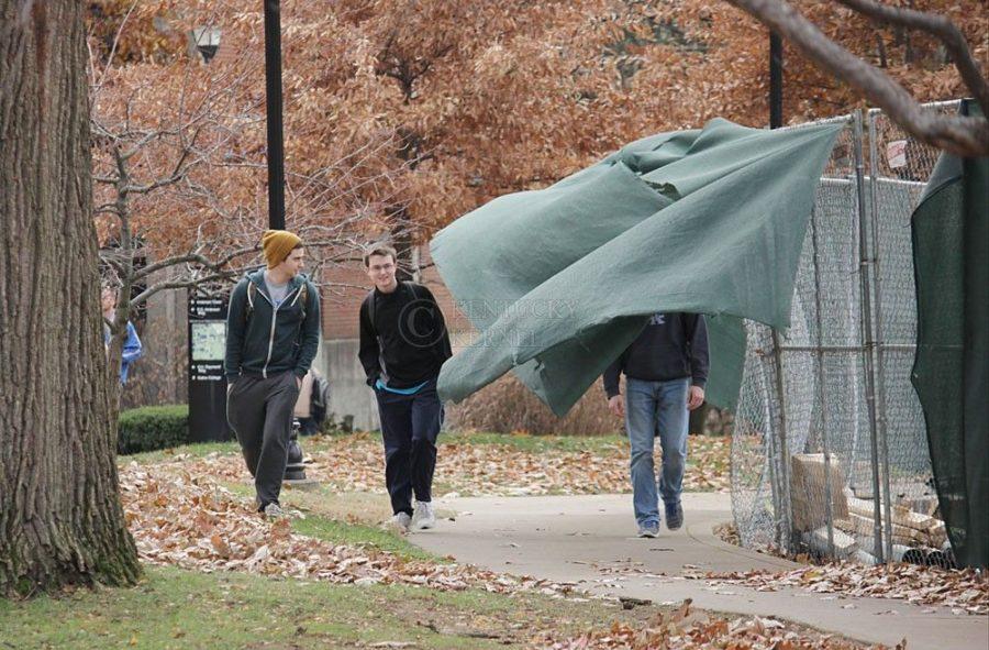 Three+students+avoid+loose+tarp+covering+a+fence+in+front+of+Business+and+Economics+building+on+a+windy+Monday+afternoon%2C+November+24%2C+2014.+Photo+by+Marcus+Dorsey
