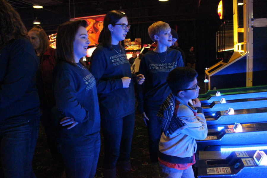 AOIIs Hailee Conrad, left, Bea Randolph, middle, and Emily Crace, right, watch as Joshua, age 10, plays Ski Ball at GattiTown on Dec. 7, 2017 during AOIIs Christmas With the Kids. 