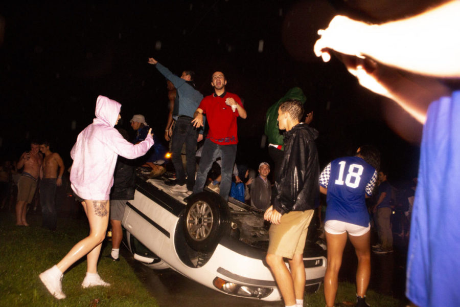 Students stand on a flipped car on State Street on Saturday, September 8, 2018 in Lexington, Kentucky after the UK football team beat the Florida Gators 27-16, ending a 31-year losing streak. Photo by Arden Barnes | Staff