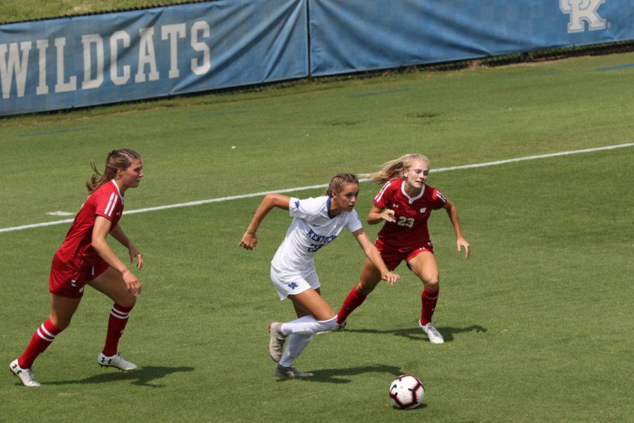 Freshman Abby Steiner (22) slipping through two opponents. University of Kentucky womens soccer received their first loss of the season against University of Wisconsin on Sunday, August 26th, 2018. Photo by Michael Clubb | Staff