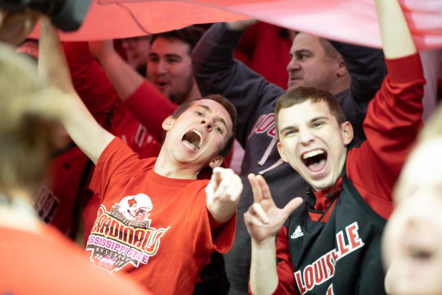 UofL fans yell for a picture while holding a giant Cards flag over the student section. University of Kentucky mens basketball team defeated University of Louisville 71-58 at the KFC Yum Center on Saturday, December 29, 2018 in Louisville, Kentucky. Photo by Michael Clubb | Staff