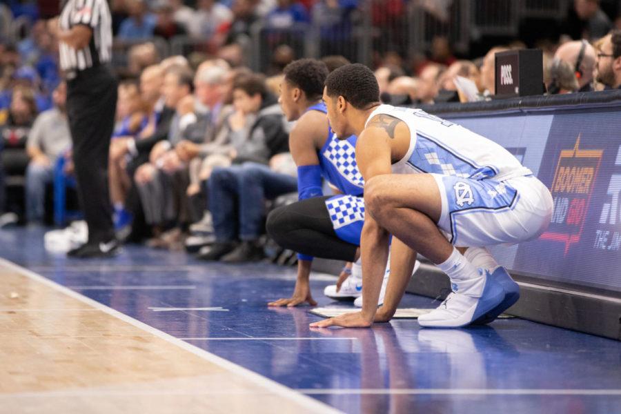 Freshman guard Ashton Hagans waiting to be put into the game while squatting next to a UNC player. University of Kentucky men's basketball team defeated University of North Carolina 80-72 in the CBS Sports Classic at the United Center on Saturday, December 22, 2018 in Chicago, Illinois. Photo by Michael Clubb | Staff