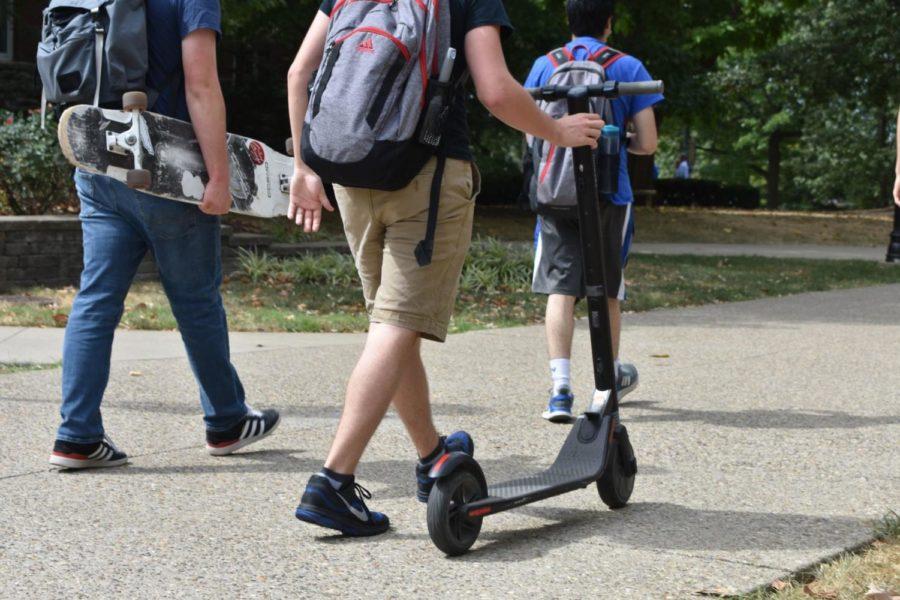 UK student Evan Shepherd wheels his electric scooter across campus as he walks with his friends on Thursday, September 26, 2019 in Lexington, Kentucky. Photo by Natalie Parks | Staff