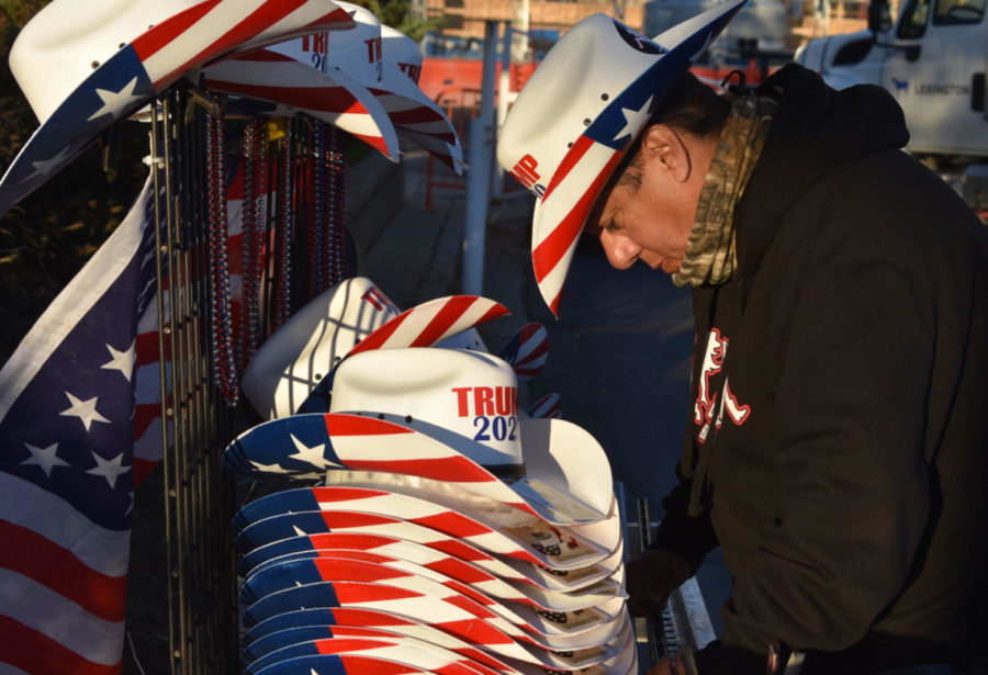 Biskit leans over his cowboy hats, making sure everything is stacked well, as he sells merchandise outside of the presidents rally in Lexington.