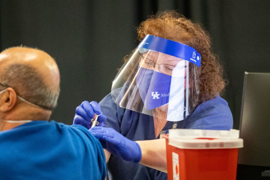 A volunteer from UK administers the COVID-19 vaccine to a recipient on UKs first day operating its vaccine clinic out of centralized Kroger Field location. Photo by Michael Clubb | Staff.