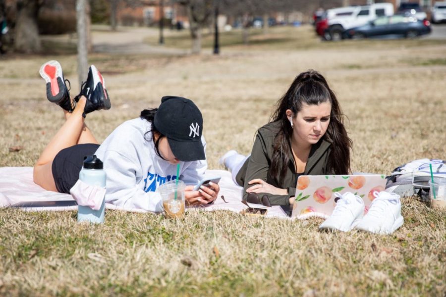 Two UK students sign up for graduation, which UK announced on March 12 would take place in person at Rupp Arena May 14-16, while enjoying the early spring weather on the University of Kentuckys campus on Wednesday, March 11, 2021. Photo by Jack Weaver | Staff