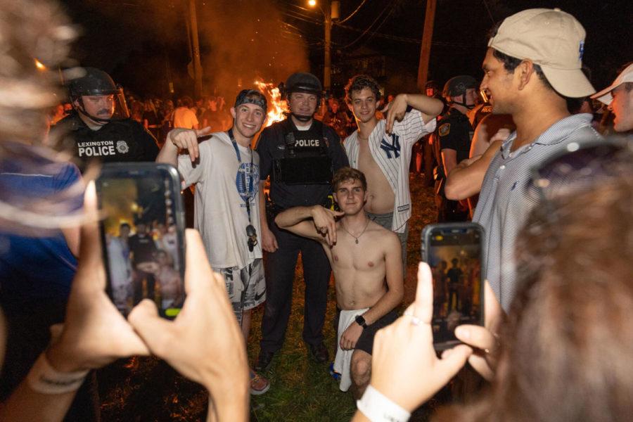 A group of UK students poses for a photo with a Lexington police officer during a student celebration after Kentucky football defeated No. 10 Florida on Saturday, Oct. 2, 2021, on Crescent Avenue in Lexington, Kentucky. Photo by Jack Weaver | Staff