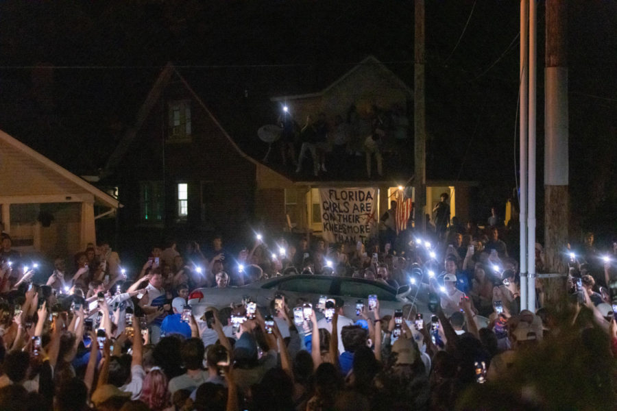 People surround a flipped car on State Street after UK fans gathered following Kentucky football's win over Florida on Sept. 10, 2022. Photo by Isabel McSwain | Kentucky Kernel