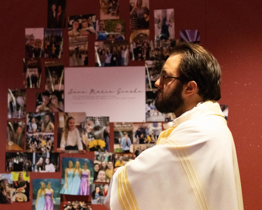 Rev. Ben Horn walks past photos of Anne Marie Gieske at a memorial mass for Gieske on Thursday, Nov. 3, 2022, at the Catholic Newman Center in Lexington, Kentucky. Photo by Abbey Cutrer | Staff