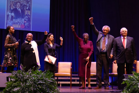 Panelists on stage raise their fists during the Civil Rights Leader Panel at the Dr. Martin Luther King Jr. 50th Anniversary Celebration at The Singletary Center in Lexington, Kentucky, on January 17, 2023. From left to right are Betty Baye, Aaron-Ann Funfsinn, Mattie Jones, John Johnson, and Charles Neblett. Photo by Samuel Colmar | Kentucky Kernel