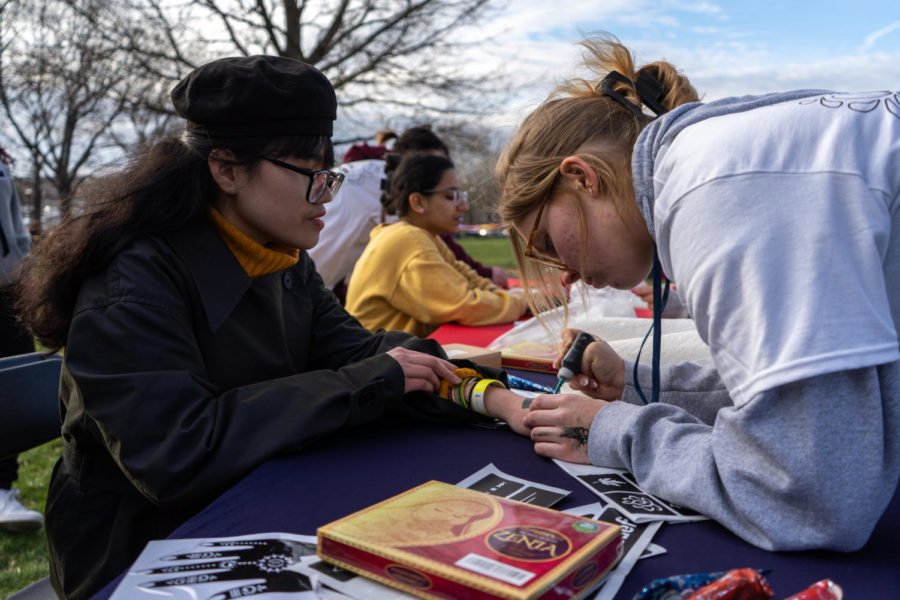 A student watches as a henna artist paints henna on her hand during the Holi celebration put on by the Student Activities Board and Indian Student Association on Wednesday, March 8, 2023, at the Main Lawn in Lexington, Kentucky. Photo by Carter Skaggs | Staff