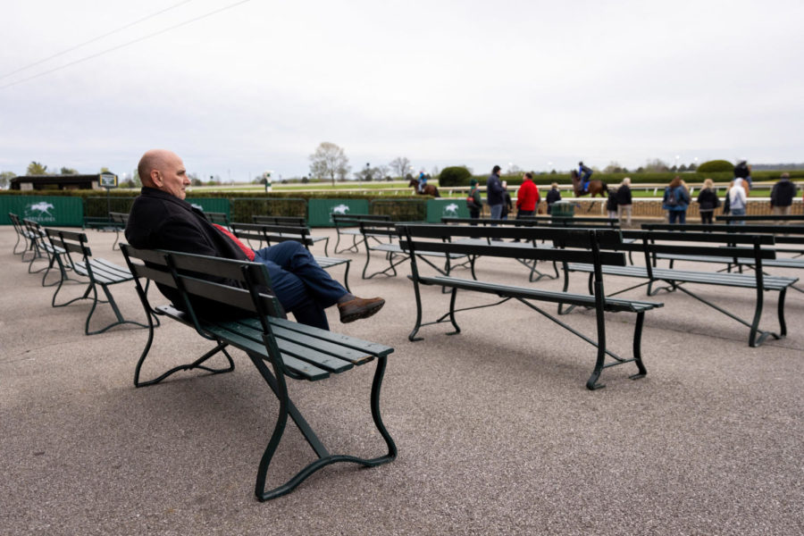 A spectator sits on a bench beneath the grandstand as horses exercise on the main track during morning training on the opening day of the Spring Meet on Friday, April 7, 2023, at Keeneland in Lexington, Kentucky. Photo by Jack Weaver | Staff