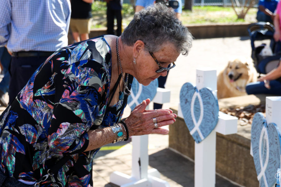 Betsy Bryant bows at the makeshift memorial displays honoring the victims of the mass shooting in Louisville during the community vigil on Wednesday, April 12, 2023, at the Muhammad Ali Center plaza in Louisville, Kentucky. Bryant said she’s heartbroken about her city. Kentucky Lantern photo by Abbey Cutrer