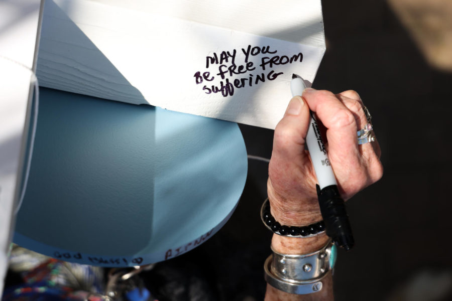 Betsy Bryant signs a makeshift memorial display for a victim of the mass shooting in Louisville during the community vigil on Wednesday, April 12, 2023, at the Muhammad Ali Center plaza in Louisville, Kentucky. Kentucky Lantern photo by Abbey Cutrer