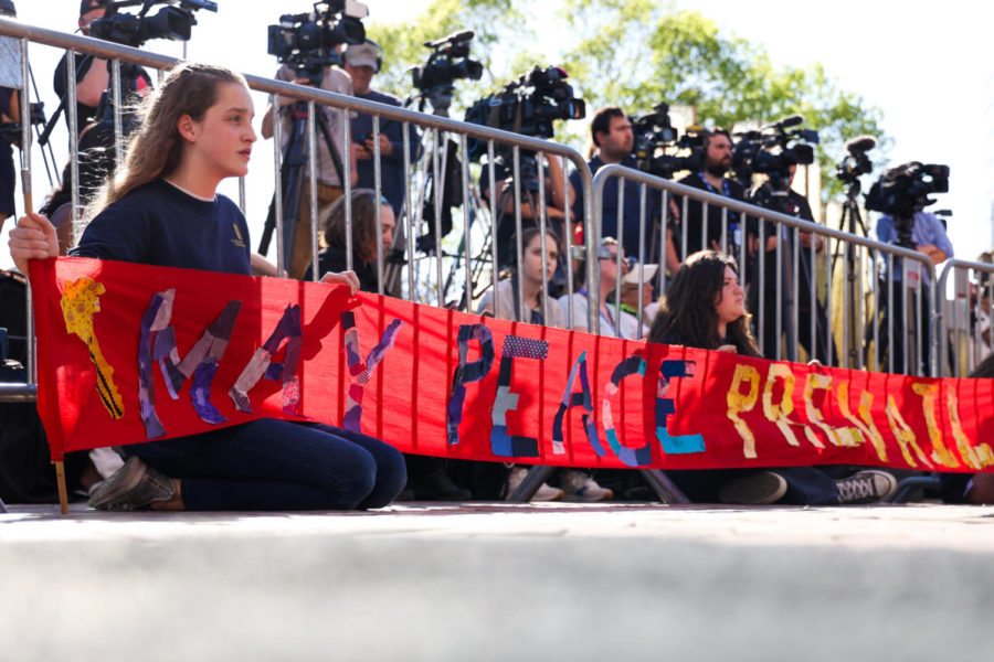 Johanna Hawley (left) and Ava Donnis hold a sign that reads, “May peace prevail on earth” during the community vigil honoring the victims of there Louisville mass shooting on Wednesday, April 12, 2023, at the Muhammad Ali Center plaza in Louisville, Kentucky. Kentucky Lantern photo by Abbey Cutrer