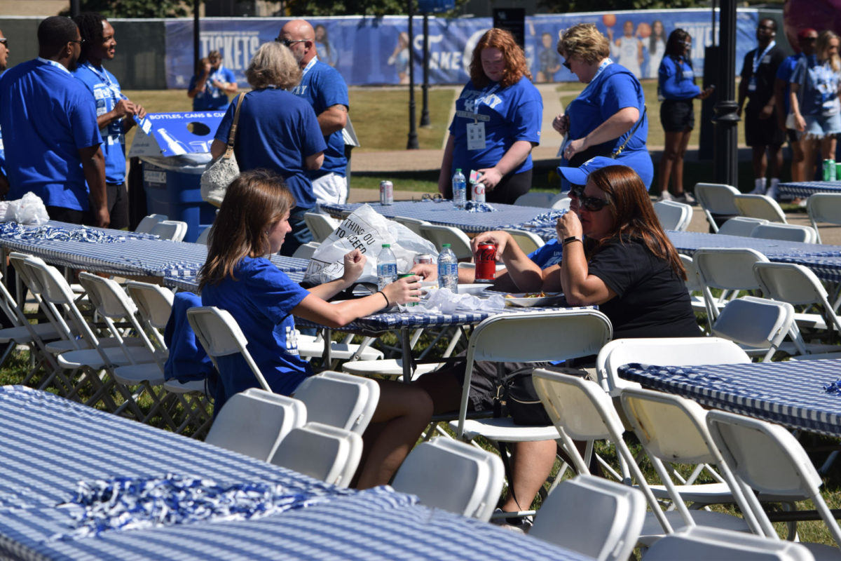 A family sits down to eat at the University of Kentucky Family Weekend Tent Party on Saturday, Sep. 23, 2023 at Stoll Field in Lexington, Kentucky. Photo by Gracie Moore | Staff