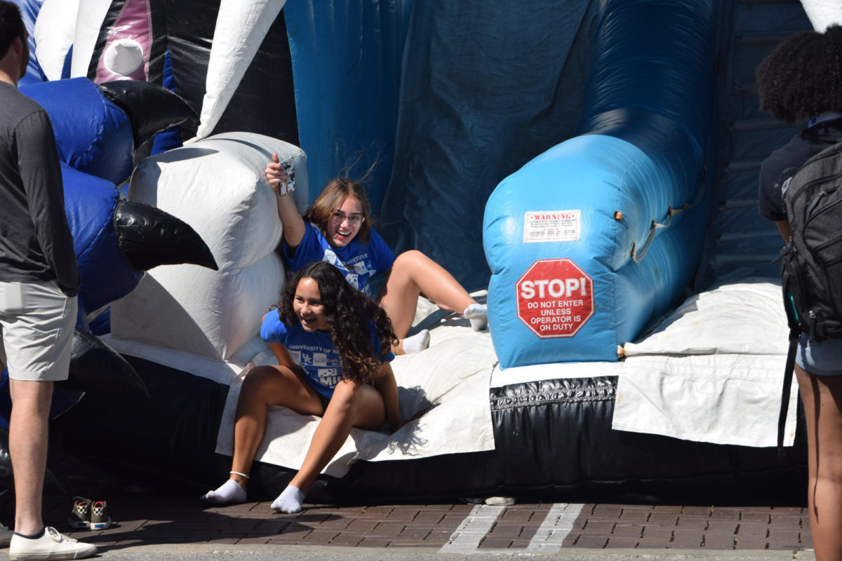 Zoey Dix, a freshman architecture major, and high school student Taylor Lepolo reach the end of the inflatable slide at the University of Kentucky Family Weekend Tent Party on Saturday, Sep. 23, 2023 at Stoll Field in Lexington, Kentucky. Photo by Gracie Moore | Staff