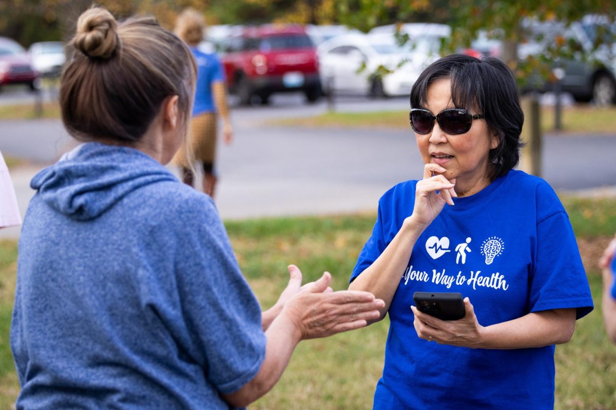 An organizer speaks with a participant before the Walk With a Doc event on Tuesday, Oct. 24, 2023, at the Arboretum, State Botanical Garden of Kentucky in Lexington, Kentucky. Photo by Samuel Colmar | Staff