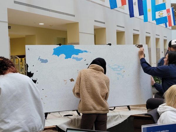 Students paint a mural displaying William T. Young Library on Tuesday, Nov. 28, 2023, in the atrium of William T. Young Library in Lexington, Kentucky. Photo by Adah Hufana