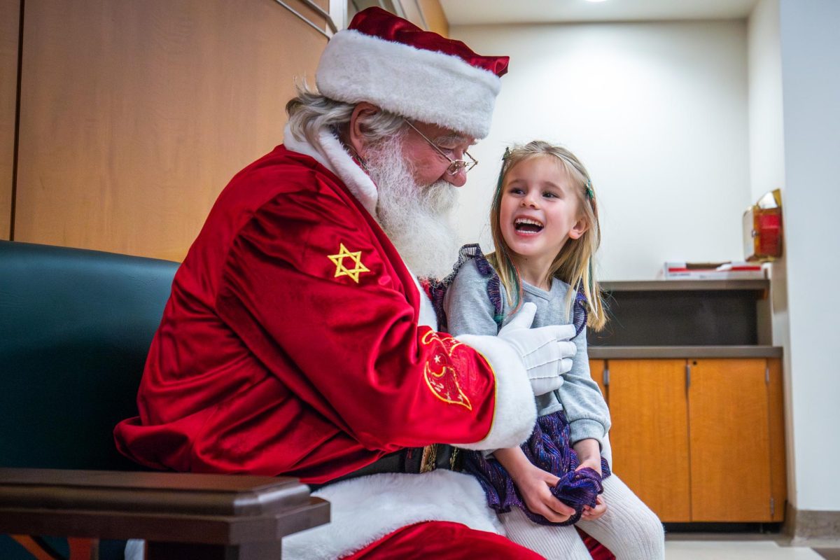 A child attendee sits with Santa during the Breakfast with Santa event on Saturday, Dec. 2, 2023, at the Kentucky Childrens Hospital in Lexington, Kentucky. Photo by Samuel Colmar | Staff