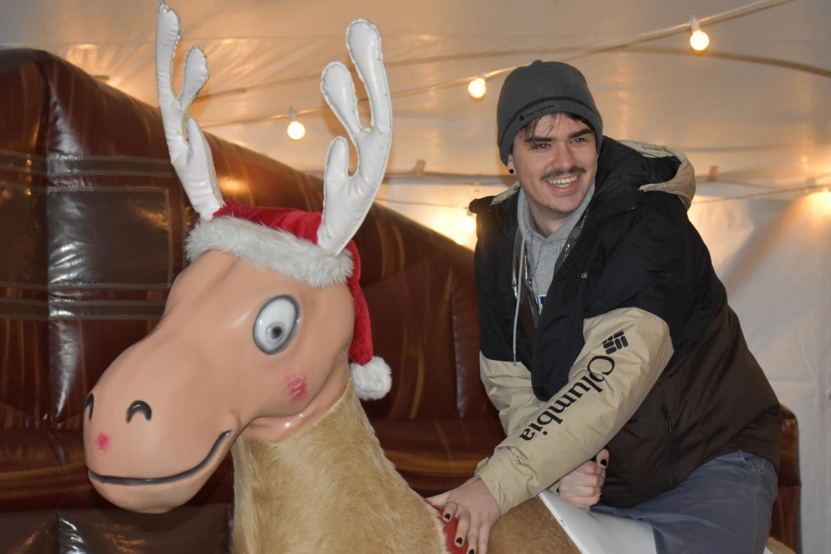 Sophomore computer engineering major Alex Franzoni rides a mechanical reindeer during the Woodland Wonderland event hosted by Campus Housing on Wednesday, Jan. 10, 2024, at the South Campus Lawn in Lexington, Kentucky. Photo by Sydney Yonker | Staff
