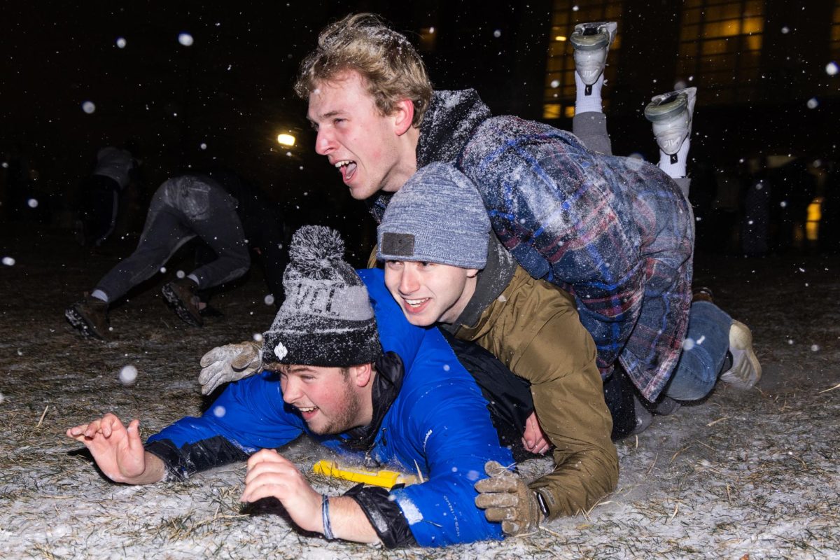 Students piled on top of each other sled down the bowl outside William T Young Library on top of a wet floor sign on Sunday, Jan. 14, 2024, during the first snow on campus outside William T Young Library in Lexington, Kentucky. Photo by Samuel Colmar | Staff