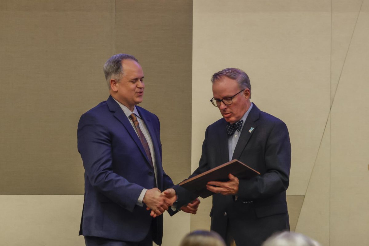 Duane Bonifer hands Peter Baniak his award as he is inducted into the Kentucky Journalism Hall of Fame on Tuesday, April 9, 2024, at University of Kentucky in Lexington, Kentucky. Photo by Matthew Mueller | Staff