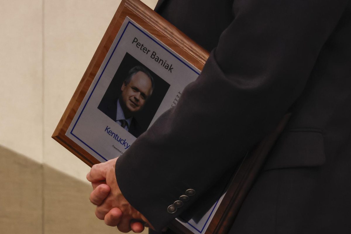 Duane Bonifer holds Peter Baniak’s plaque during Baniak’s speech during the Kentucky Journalism Hall of Fame induction on Tuesday, April 9, 2024, at University of Kentucky in Lexington, Kentucky. Photo by Matthew Mueller | Staff