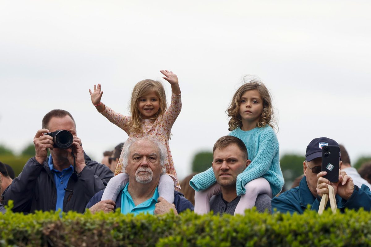 Children wave as horses enter the track on Friday, April 19, 2024, at Keeneland During College day in Lexington, Kentucky. Photo by Matthew Mueller | Staff