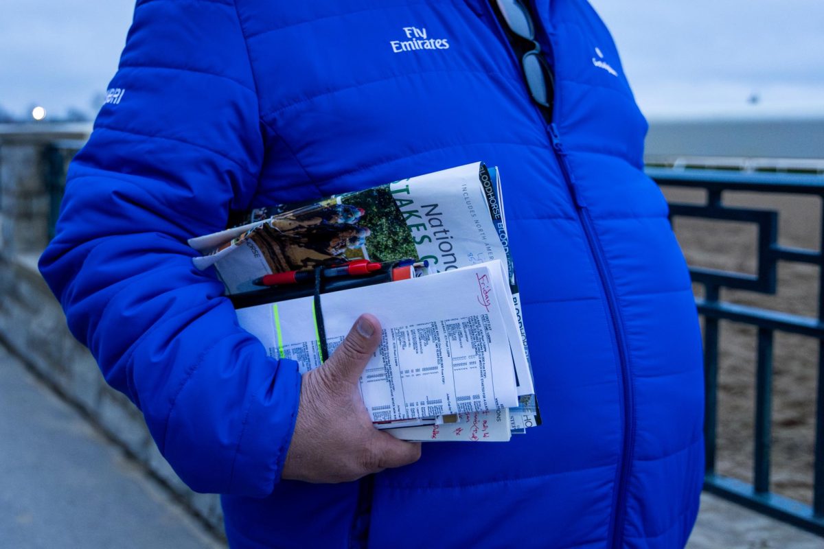 An attendee holds magazines and papers containing information on opening day at Keeneland during morning training on the opening day of the Spring Meet on Friday, April 5, 2024, at Keeneland in Lexington, Kentucky. Photo by Samuel Colmar | Staff