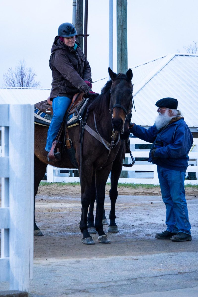 An exercise rider stops and lets a man pet their horse during morning training on the opening day of the Spring Meet on Friday, April 5, 2024, at Keeneland in Lexington, Kentucky. Photo by Samuel Colmar | Staff