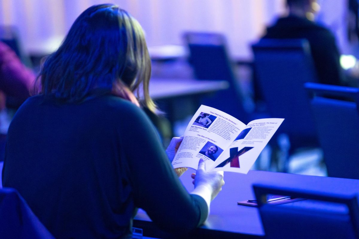 An attendee reads a pamphlet on the event during the TEDxUKY Trailblazing event on Friday, April 12, 2024, at the Gatton Student Center Grand Ballroom in Lexington, Kentucky. Photo by Samuel Colmar | Staff