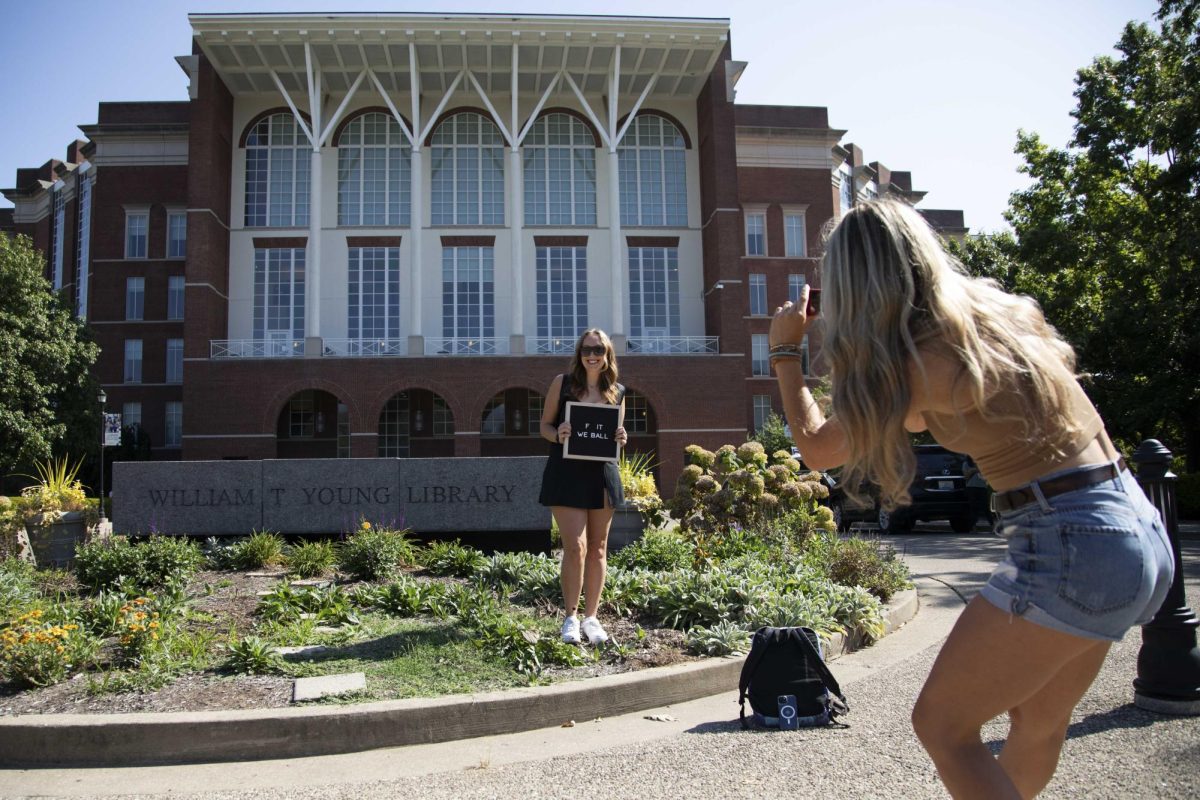 Ashley Pence, Senior Agricultural Economics student, poses in front of William T. Young Library with a sign for the first day of school while her friend Jada Lang, Senior Business student, takes a photo on Monday, Aug. 26, 2024, in Lexington, Kentucky. Photo by Christian Kantosky | Staff