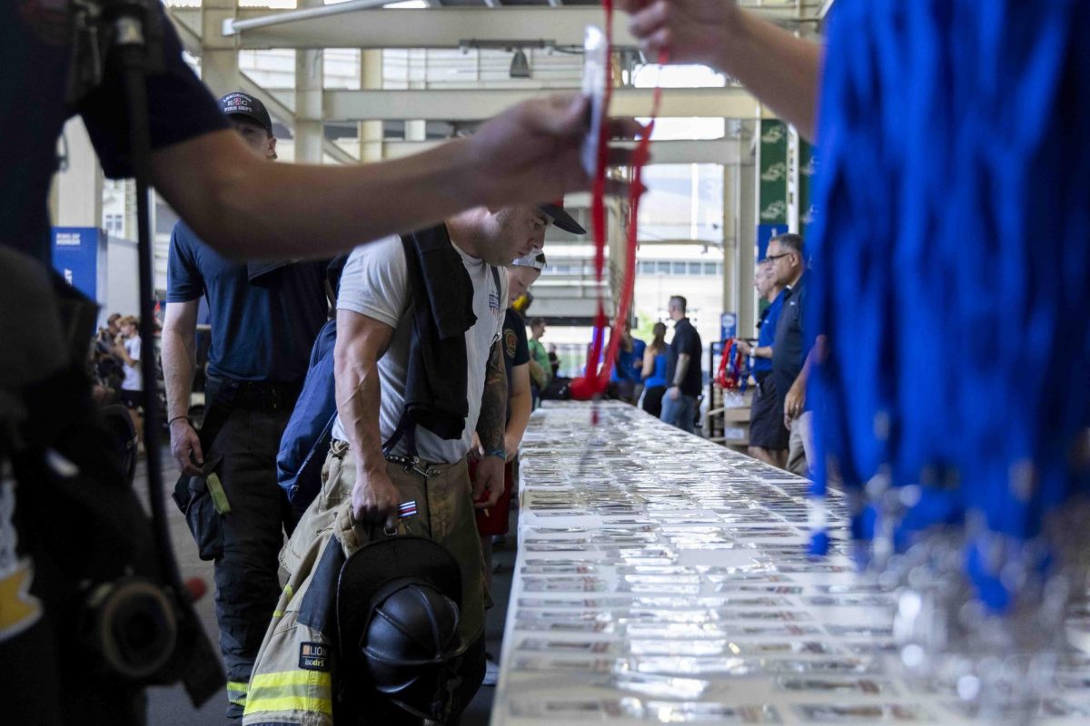 Firefighters pick out badges with 9/11 victims printed on them during the 9/11 Memorial Stair Climb on Wednesday, Sept. 11, 2024, at Kroger Field in Lexington, Kentucky. Photo by Matthew Mueller | Staff