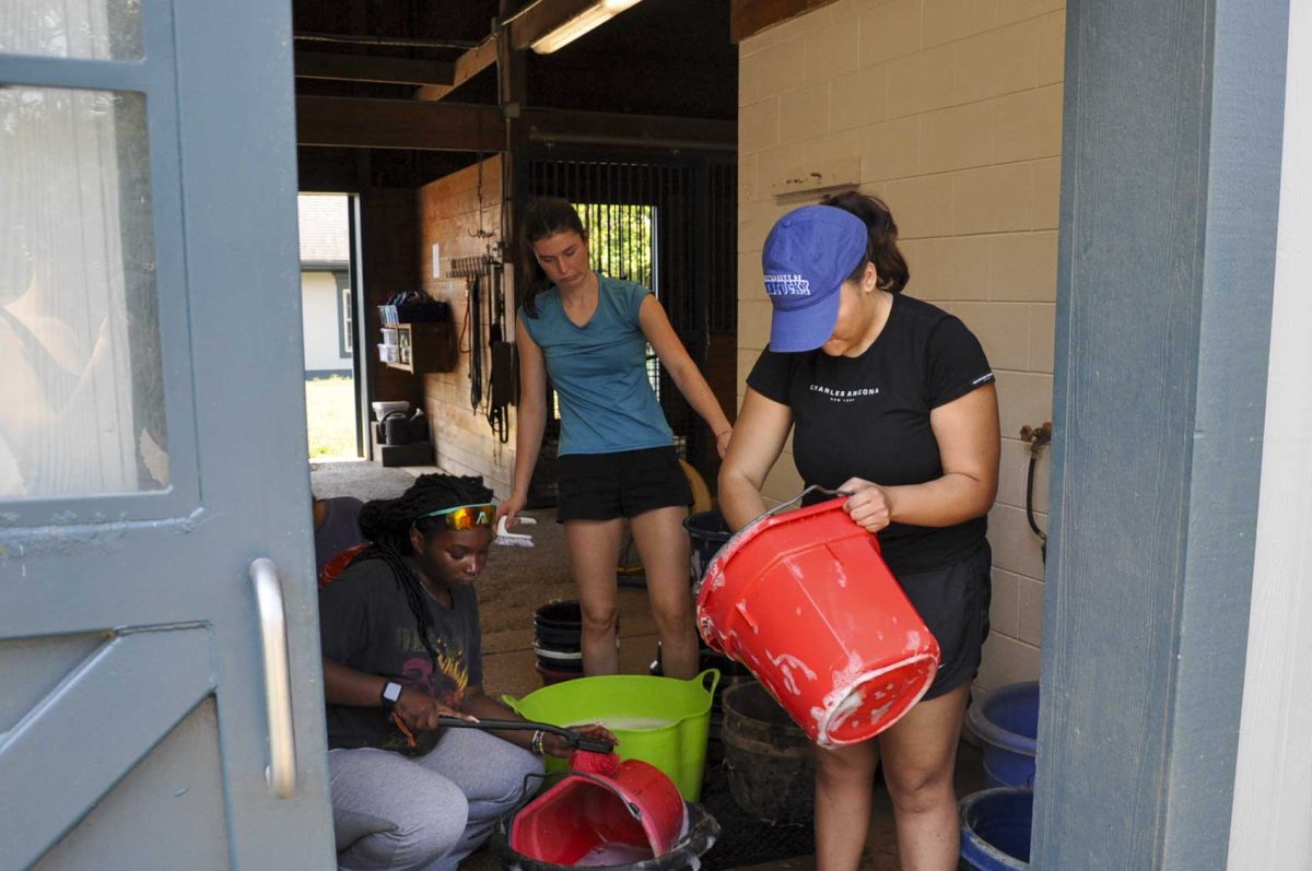 Students clean buckets used to feed the horses on Saturday, Aug. 31, 2024, at the Secretariat Center in Lexington, Kentucky. Photo by Isabella Sepahban | Staff