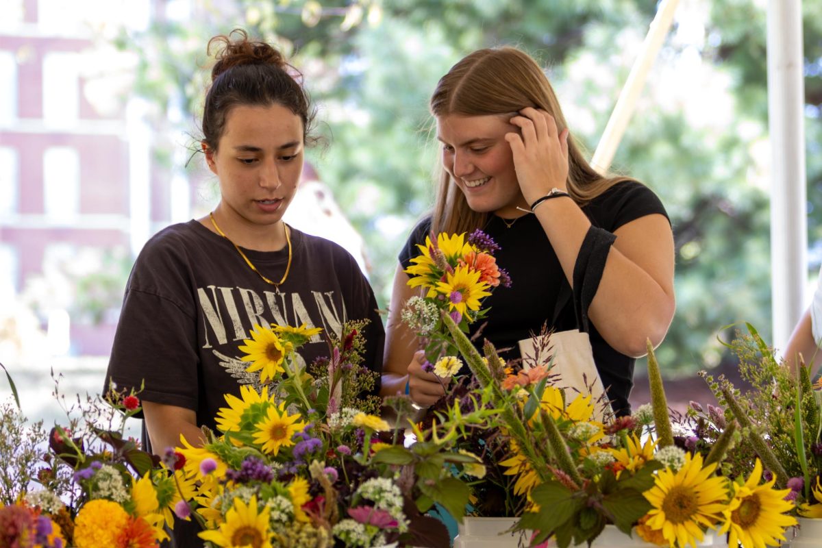 Hope Stout a freshman in Biology smiles with her friend Arwa Abd, a freshman in Neuroscience over flower selection during the Wildcat Market at the University of Kentucky on Wednesday, Sep 11, 2024. Photo by Sydney Novack | staff