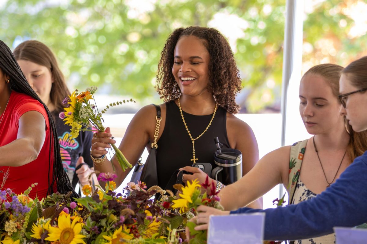 Kennedy Howard a senior in Communication, sciences, and disorders, smiles with friends while making a flower selection during the Wildcat Market at the University of Kentucky on Wednesday, Sep 11, 2024. Photo by Sydney Novack | staff