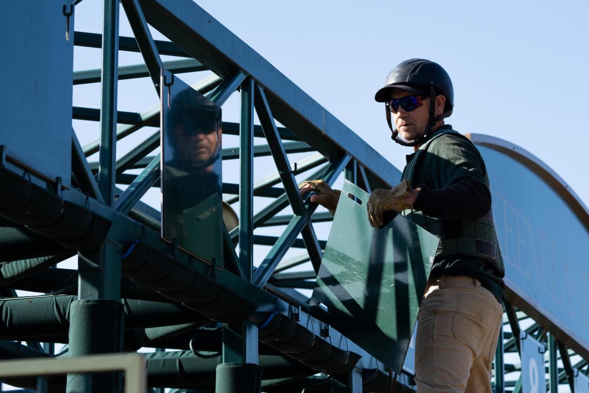 A groundskeeper climbs to rearrange the numbers on the starting gates on Friday, Oct. 18, 2024, at Keeneland in Lexington, Kentucky. Photo by Christian Kantosky | Staff