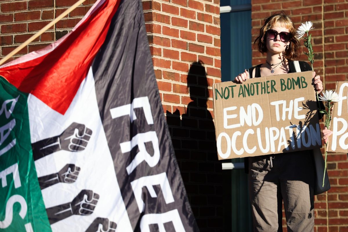 A student holds a sign and flowers at a vigil for the deaths in Palestine on Monday, Oct. 7, 2024, outside of the William T. Young Library in Lexington, Kentucky. Photo by Abbey Cutrer | Staff