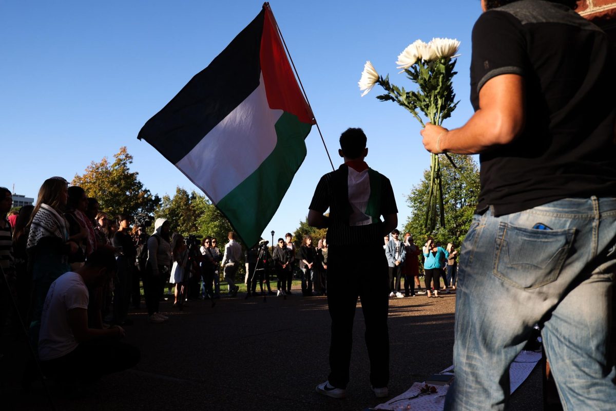 People hold flags and flowers at a vigil for the deaths in Palestine on Monday, Oct. 7, 2024, outside of the William T. Young Library in Lexington, Kentucky. Photo by Abbey Cutrer | Staff