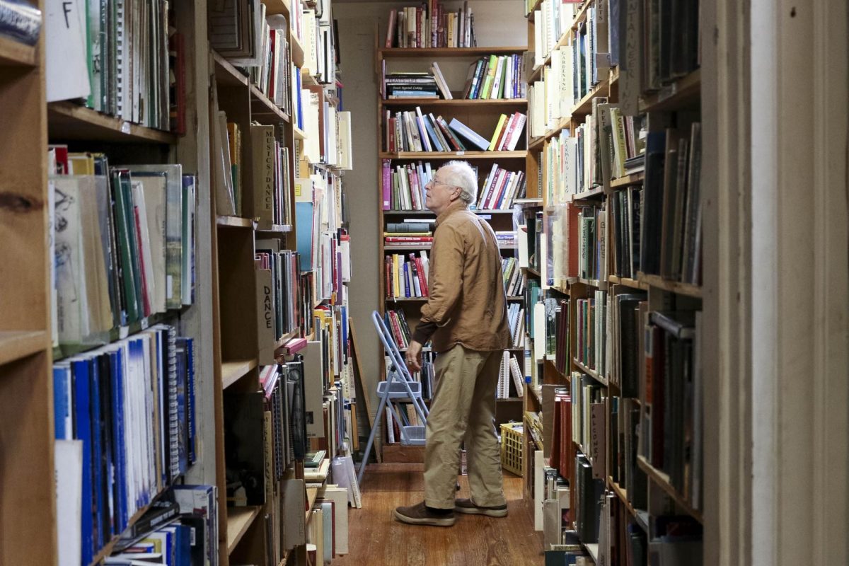 John Glover looks up at shelf to find a book in his store, Glover's Bookery, on Saturday, Nov. 9, 2024, in Lexington, Kentucky. Photo by Isabella Sepahban | Staff