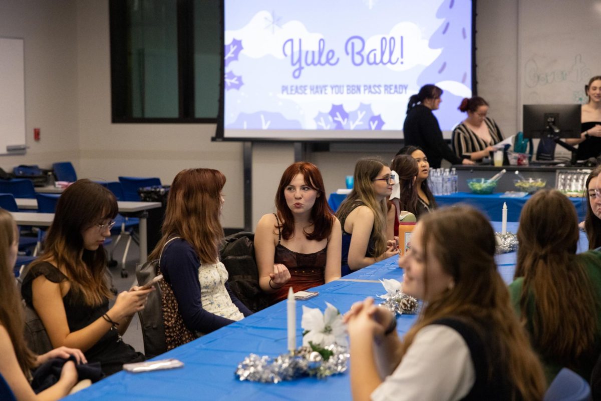 Erika Hartman a freshman Biology major talks to friends during the Yule Ball Cover to Cover meeting on Wednesday, Dec. 4, 2024, at Don & Cathy Jacobs Science Building in Lexington, Kentucky. Photo by Sydney Yonker | Staff