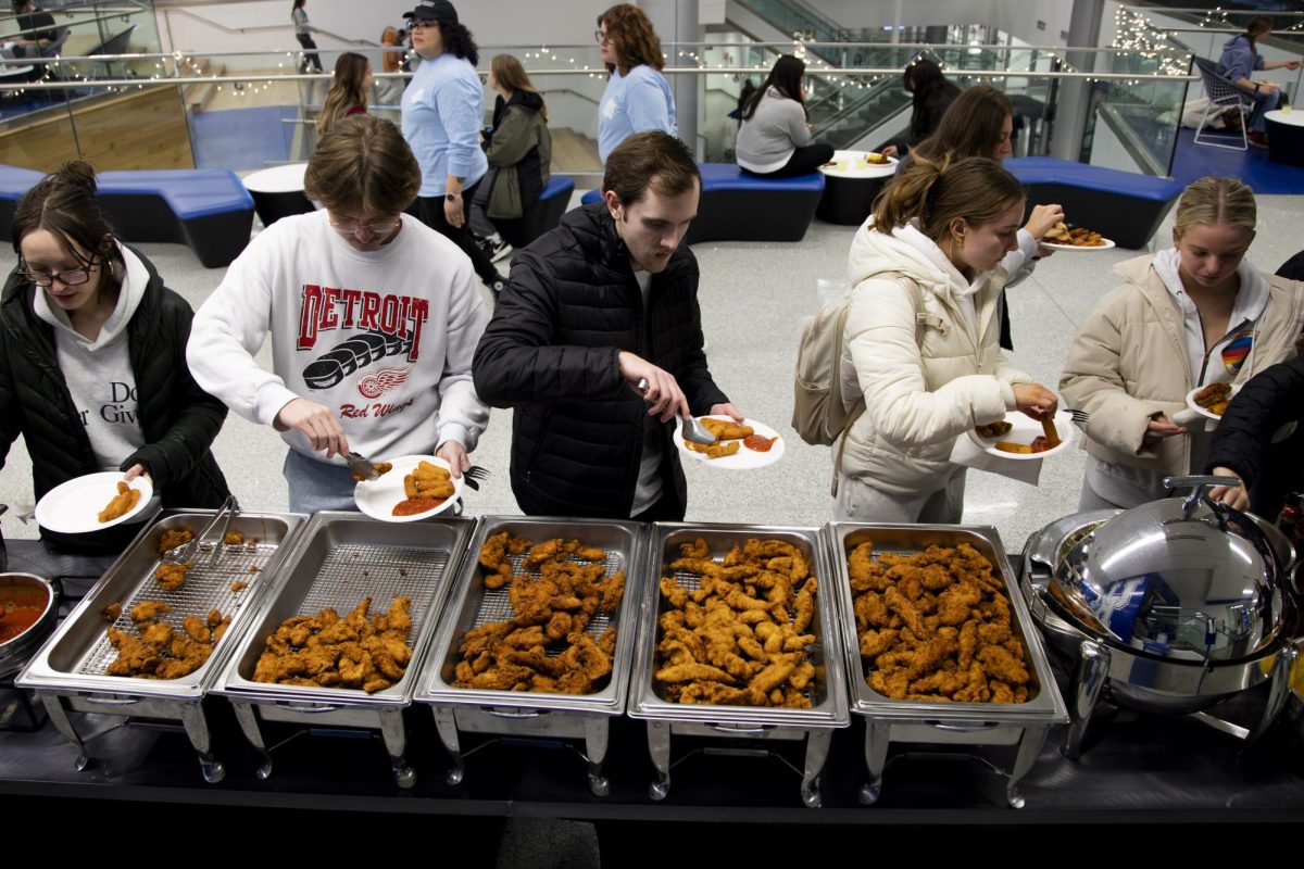 Students fill their plates with chicken tenders before grabbing waffles during the Crunch Brunch event on Sunday, Dec. 8, 2024, at the Gatton Student Center in Lexington, Kentucky. Photo by Christian Kantosky | Assistant Photo Editor