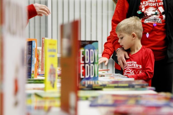 A young volunteer looks at books during the Firefighter Toy Drive on Saturday, Dec. 14, 2024, at the Lexington Fire Fighter North Pole off New Circle Road in Lexington, Kentucky. Photo by Christian Kantosky | Assistant Photo Editor