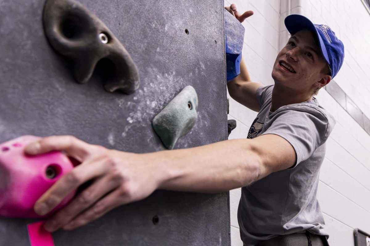 A member of the Rock Climbing Club looks over at other members climbing on the wall during the weekly club meeting for the UK Rock Climbing Club on Wednesday, Dec. 4, 2024, at Johnson Center in Lexington, Kentucky.  Photo by Matthew Mueller | Photo Editor