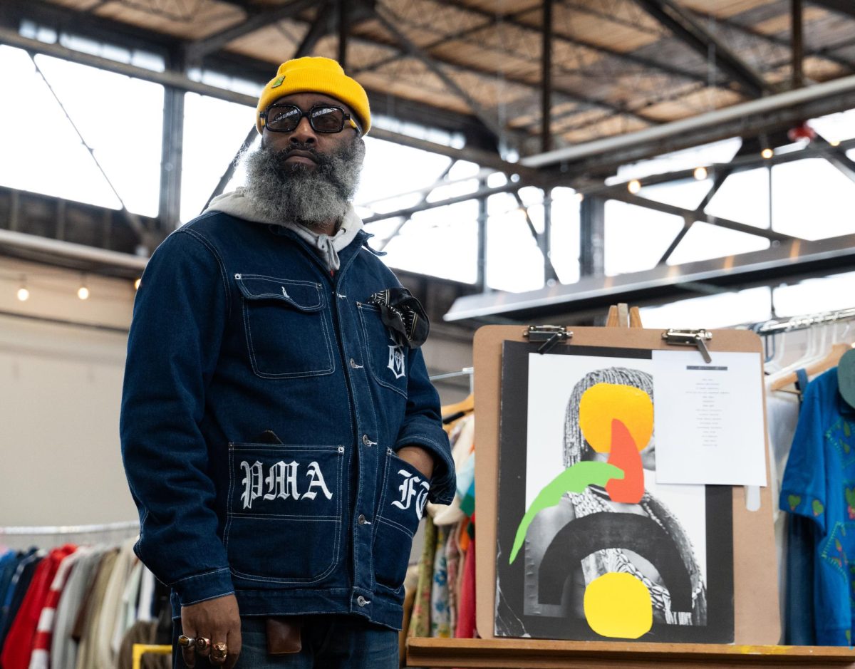 Guleus S’Xavier stands in front of his artwork Vintage Festival on Saturday, Nov. 23, 2024, at Greyline Station in Lexington, Kentucky. Photo by Brayden Finn | Staff