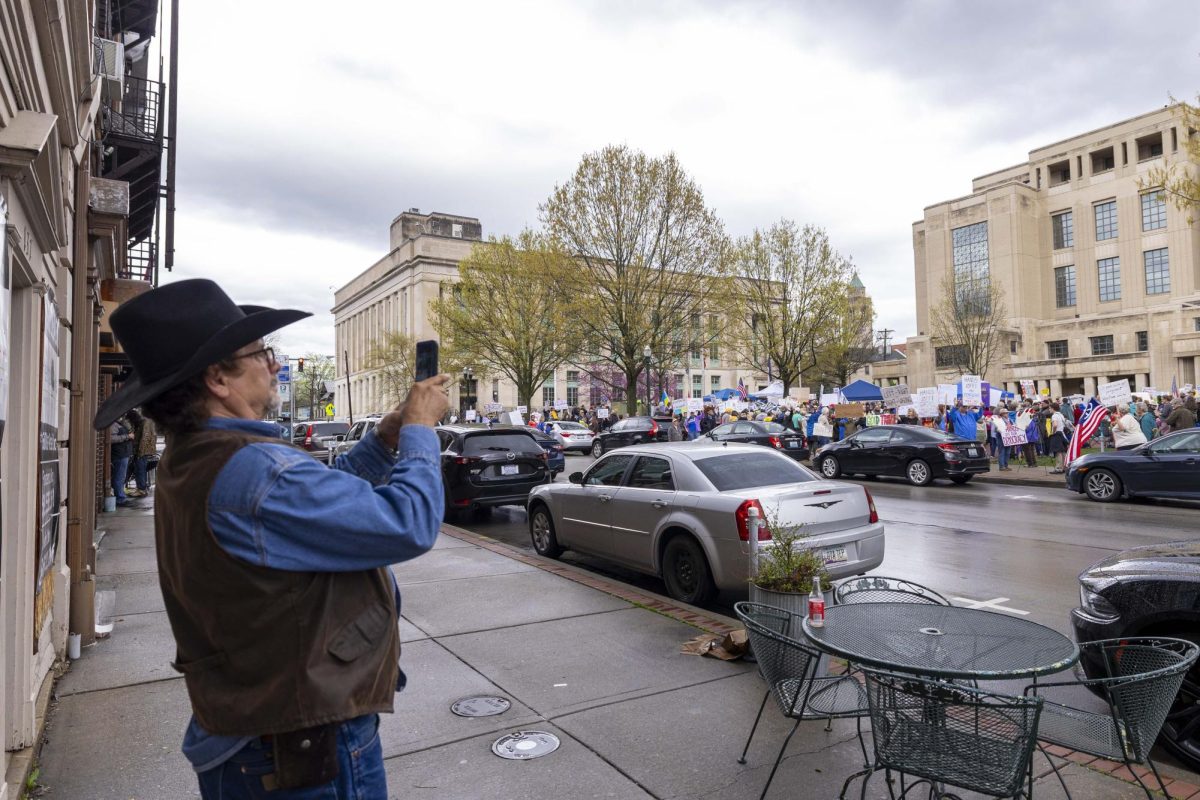 A pedestrian takes a photos of the protesters during the “Hands Off!” protest on Saturday, April. 5, 2025, at Robert F. Stephens Courthouse Plaza in Lexington, Ky Photo by Matthew Mueller | Photo Editor