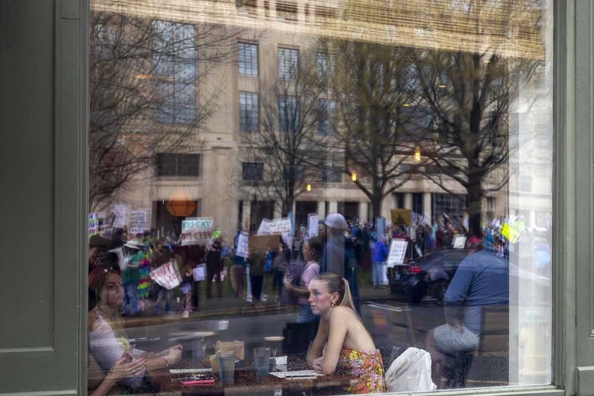 People sit inside of a resturant while protesters stand outside during “Hands Off!” protest on Saturday, April. 5, 2025, at Robert F. Stephens Courthouse Plaza in Lexington, Ky Photo by Matthew Mueller | Photo Editor