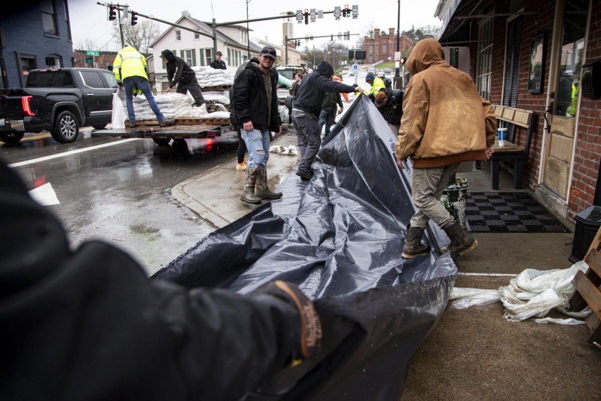 City employees and volunteers lay our more tarp to stack sandbags on as heavy rain caused the Kentucky River to flood on Sunday, April 6, 2025, at East Main Street in Frankfort, Ky. Photo by Christian Kantosky | Assistant Photo Editor
