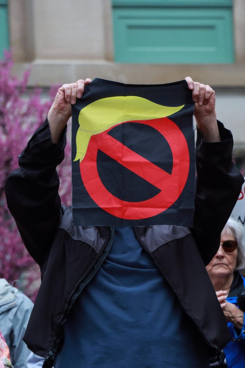 Protestor holds a flag over his face during the “Hands Off!” protest on Saturday, April 5, 2025, at Robert F. Stephens Courthouse Plaza in Lexington, Ky. Photo by Cara Raiford | Staff